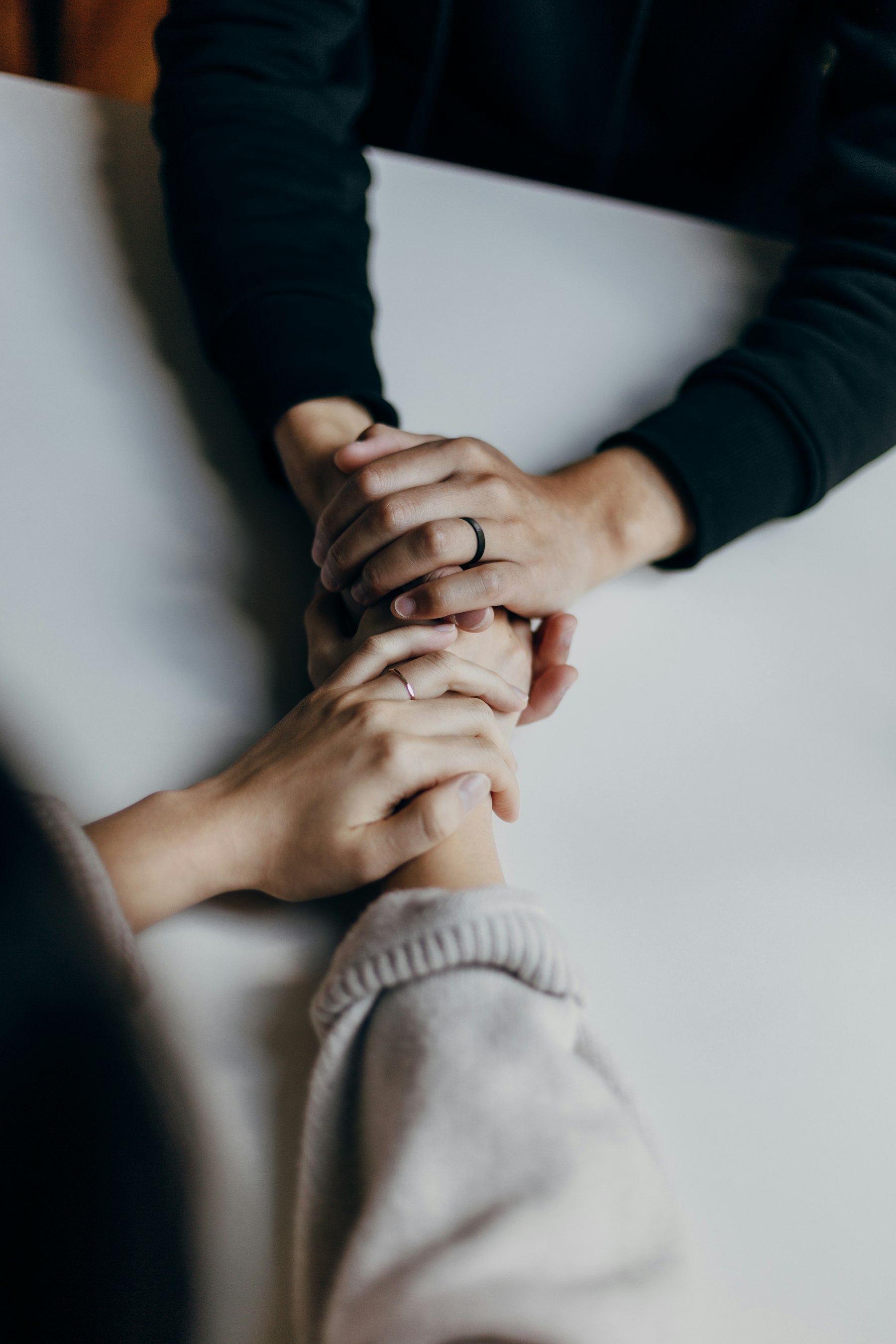 Dos personas tomadas de las manos sobre una mesa, en un gesto de acompañamiento